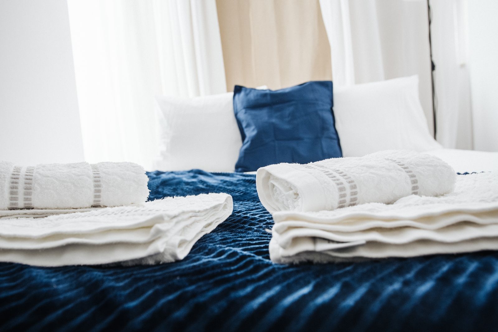 Rolled and folded white towels staged on a freshly made bed