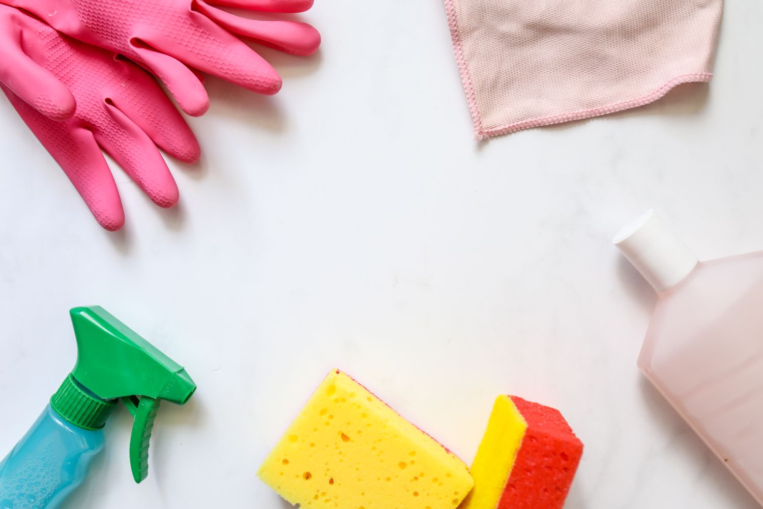 Rubber gloves, sponges, a spray bottle, and cloths laid out for cleaning